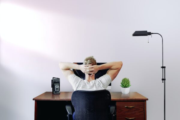 Man sitting at a desk and thinking with his hands behind his head