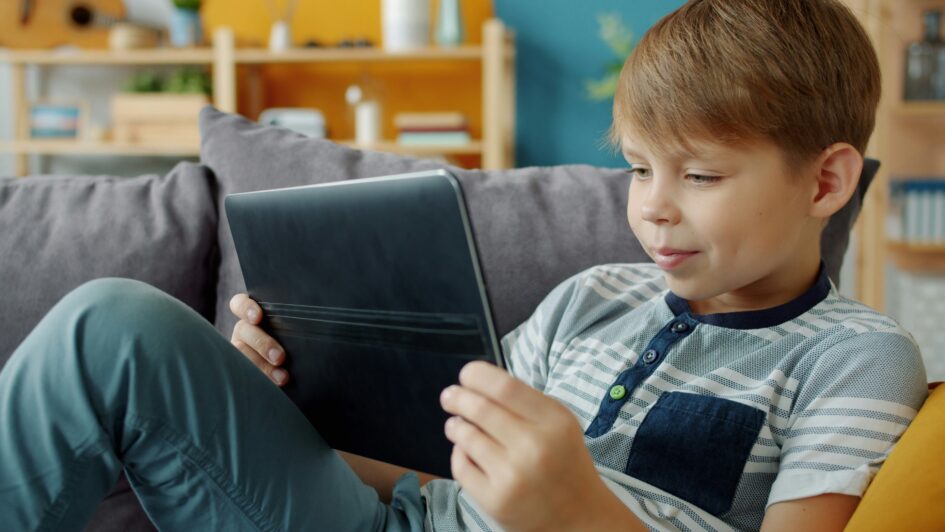 Child smiling and holding iPad